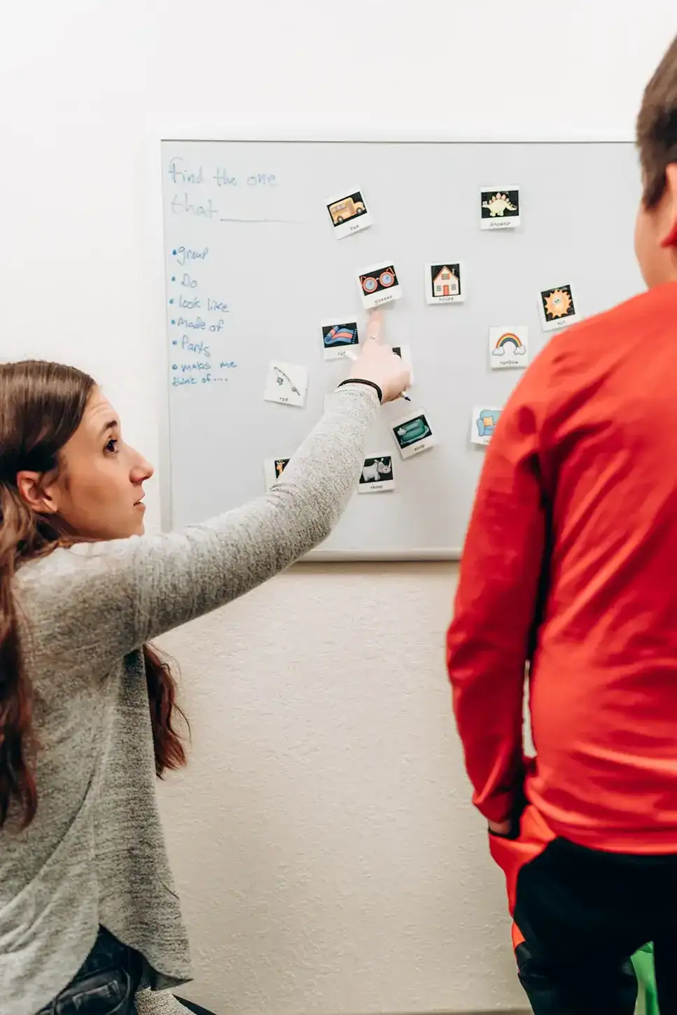Rodzice obserwują przez szybę jak dziecko ćwiczy z logopedą w gabinecie
